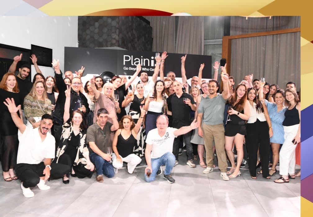 The PlainID team celebrating in front of a PlainID banner